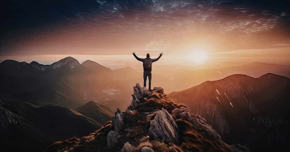 Hiker on a jagged mountain peak with arms raised toward the sunrise over a valley below.